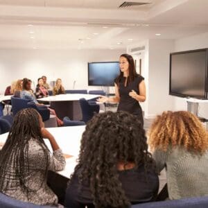 A woman giving a Seminar to a group of people in a conference room.